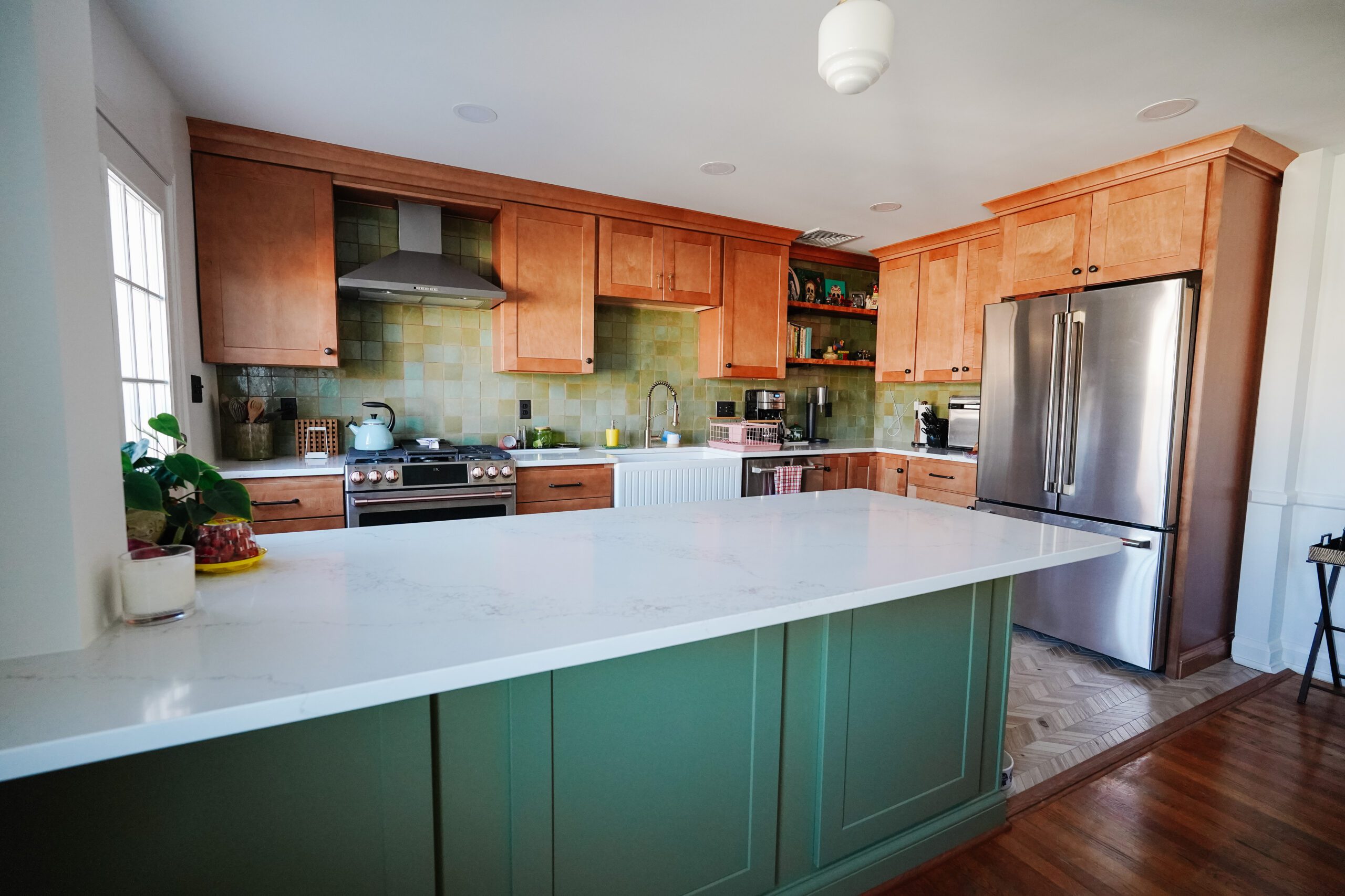 Kitchen island with a white countertop and green base, by GranitePro