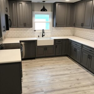Kitchen with dark gray cabinetry and white countertops