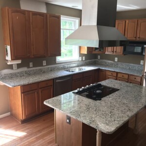 Kitchen with wood cabinetry and speckled granite-look countertops