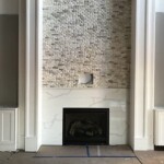 Fireplace with a white veined surround and stone tile wall
