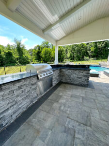 Outdoor kitchen with stacked stone base under a pavilion
