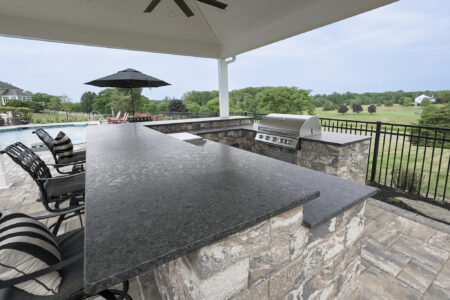 Outdoor kitchen with black countertops and bar seating